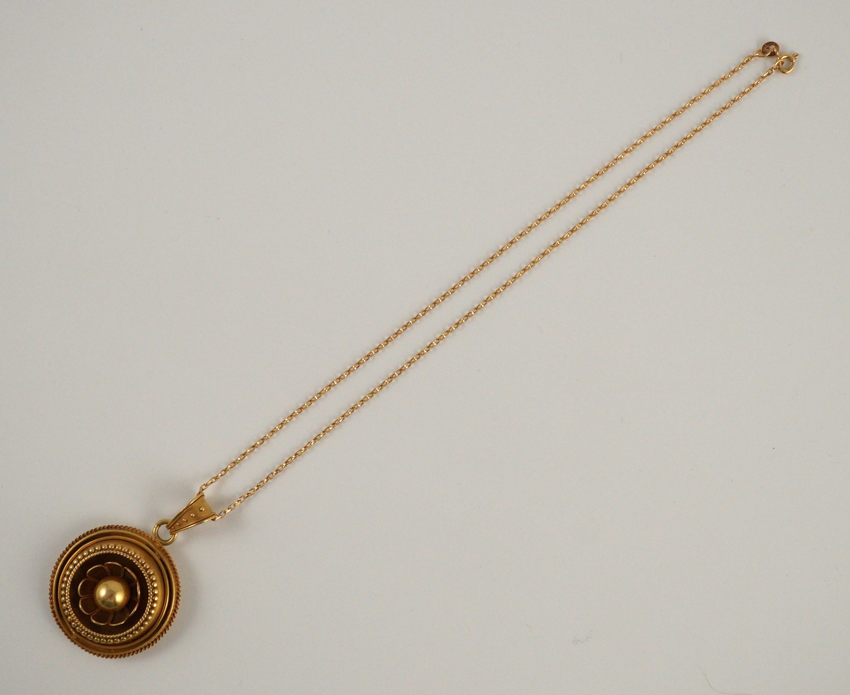 A Victorian gold circular pendant, with flower head centre and glazed back, on a later 9ct gold chain
